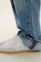 Zapatillas deportivas blancas con detalles plateados y suela color caramelo.