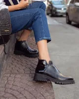 Botines negros de cuero con elástico lateral, detalle charol en el talón y suela track.