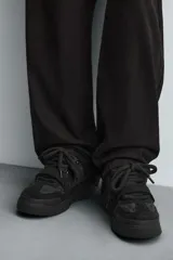 Zapatilla estilo skate de diseño robusto, confeccionada en una combinación de piezas de gamuza y material textil acolchado. Presenta un sistema de cierre con cordones gruesos y una tira de velcro en el empeine, junto con una suela de plataforma con relieve irregular.