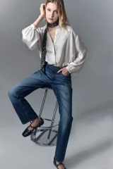 Jean de tiro alto y calce recto, confeccionado en denim azul rígido. Presenta un diseño de hotfix brillante en forma de guitarra en el frente de la pierna derecha.