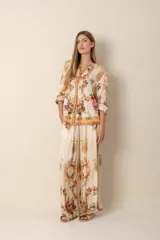 Pantalón palazzo color crema con estampado floral y de arabescos dorados.