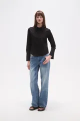 Camisa blanca de algodón, entallada, con cuello camisa y cierre frontal de botones. Presenta mangas largas con puños sencillos.