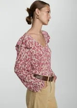 Blusa de manga larga con estampado floral en tonos rosa y blanco, escote en V, volantes en los hombros y puños elásticos.