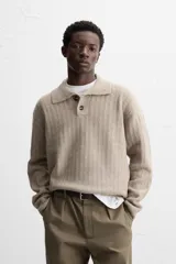 Sweater color beige de punto canalé con cuello polo, solapas amplias y cierre frontal con dos botones.