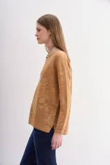 Sweater color ocre con diseño floral en jacquard y lurex a tono, escote redondo y mangas largas.