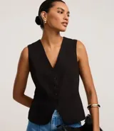 Chaleco negro de sastre, corte slim, sin mangas, con escote en V profundo y cierre frontal de cuatro botones. Presenta un bolsillo o falso bolsillo a la altura del pecho y está forrado.