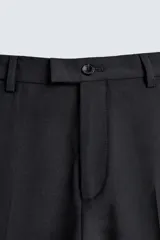 Pantalón de vestir negro de corte relaxed fit confeccionado en tejido con lana. Cuenta con bolsillos frontales y traseros de doble vivo con botón. Cierre frontal con cremallera y botón.