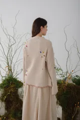 Sweater beige de lana con cuello redondo y mangas largas. Presenta detalles de bichos tejidos a contratono en la parte superior delantera.