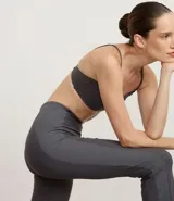 Pantalón deportivo femenino de microfibra, color gris oscuro, modelo flare (campana) con cintura alta. Presenta costuras visibles en contraste.