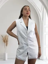 Chaleco largo blanco de corte sastrero con solapas, sin mangas y con cierre de dos botones.