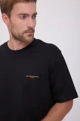 Camiseta negra de manga corta con cuello redondo y corte amplio. Estampado en la espalda con un paisaje y texto en color naranja.