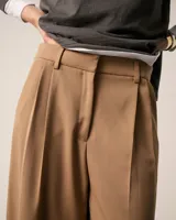 Pantalón pinzado sastrero color marrón claro, confeccionado en tela italiana de lana y elastano, de tiro medio/alto y largo hasta los tobillos. Presenta una silueta baggy, cintura prearmada, cartera con cierre y botón, bolsillos laterales funcionales y doble pinza en cada pierna. En la espalda, pinzas y un bolsillo ojal con presilla y botón.