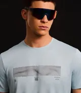 Remera deportiva celeste de poliéster con tecnología Dry, cuello redondo y mangas cortas. Estampa geométrica horizontal en el pecho y recortes en las mangas.