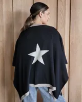 Ruana negra de tejido de punto con una estrella grande color beige en la espalda y borde inferior con franja beige.