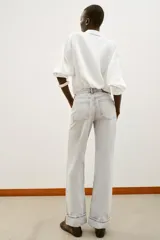 Jeans de tiro alto color negro lavado, con cintura cruzada, cinco bolsillos y pernera recta. El bajo está acabado en vuelta y tiene cierre frontal cruzado con cremallera y botones.