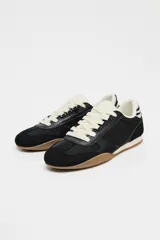 Zapatillas deportivas negras con detalle de estampado animal en la parte trasera, suela color caramelo y ajuste con cordones.