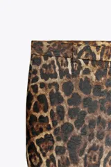 Pantalón de tiro medio con estampado animal, cintura con trabillas, bolsillos laterales ocultos y cierre frontal con cremallera, botón y ganchos metálicos.