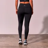 Calza deportiva larga color negro, de tiro alto y corte ajustado, con paneles de tela de red transparente en los laterales.