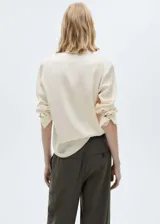 Camisa color crema de manga larga con puños abotonados y cuello camisero.
