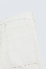 Bermuda de denim color blanco roto con efecto encerado, corte amplio (baggy fit) y cinco bolsillos. Presenta cierre frontal con cremallera y botón.