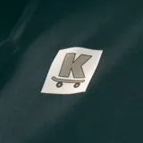 Canguro negro con capucha, cordones ajustables, bolsillo tipo canguro y puños y cintura acanalados. Estampado pequeño en el pecho con un logo cuadrado que contiene una letra K y un diseño de skate.