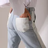 Pantalón de jean celeste con bolsillos traseros y laterales blancos.