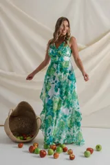 Vestido largo de gasa estampado con flores en tonos verde y blanco. Diseño cruzado con escote en V, sin mangas y falda con volados. Incluye faja en la cintura.