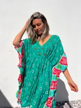 Túnica corta verde con estampado de flores rojas y detalles bordados. Mangas anchas con terminación en volados con estampado floral en tonos rosa y celeste.