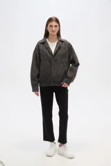 Campera de jean celeste con cuello clásico, solapas, cierre frontal con botones metálicos y mangas largas con puños abotonados. Presenta detalles de costuras diagonales y apliques de tachas metálicas.