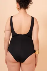 Malla entera negra con escote en V y vivos blancos en contraste. Tiene aplique de aro metálico en el cinto y bolsillo interno en el busto para colocar copa removible o prótesis externa. Confeccionada con tela que contiene fibra LYCRA® XTRA LIFE™.