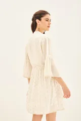 Vestido corto color blanco con estampado de lunares dorados, escote en V con detalle de bordado y mangas al codo con volantes.