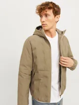 Campera híbrida color caqui, ligera e impermeable, con capucha, cierre frontal con cremallera, mangas largas con puños elásticos y bolsillos frontales con cierre.