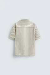 Camisa de hombre relaxed fit confeccionada en tejido de algodón a rayas verticales blancas y negras. Tiene cuello bowling, manga corta, bajo con aberturas laterales y cierre frontal de botonadura.