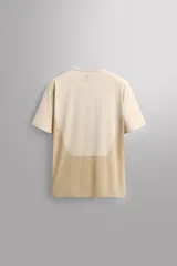 Camiseta deportiva marrón confeccionada en tejido técnico ligero y elástico con estructura perforada. Cuello redondo, manga corta y bajo asimétrico con aberturas laterales. Detalle de logo estampado.