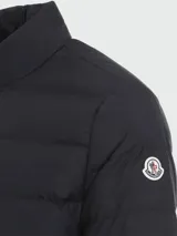 Campera puffer Moncler Baudinet color azul marino, con cuello alto, cierre frontal con cremallera, bolsillos laterales con cierre y logo de la marca en la manga izquierda.