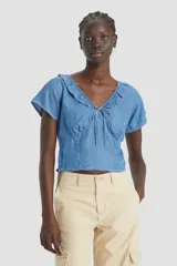 Blusa de denim fresca y ajustada, con cuello en V y detalles de volantes.