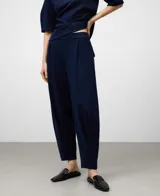 Pantalón jogger de punto color azul marino, de corte relajado y tiro alto, con pliegues frontales y puños ajustados en el tobillo.