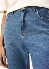 Pantalón de jean azul de corte recto y cintura alta, con terminación desflecada en el ruedo.