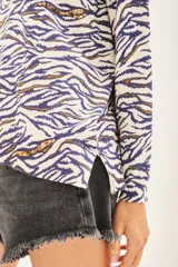 Sweater de tejido animal print con base color crema y rayas color azul y marrón. Tiene tajos laterales y lentejuelas bordadas.