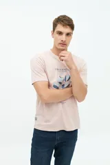 Remera color rosa pálido de manga corta con cuello redondo y estampado frontal con texto y diseño floral en tonos azules.