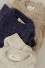 Buzo tejido en hilo de algodón color tostado, de corte holgado, con hombros caídos y diseño de ochos en la parte delantera.