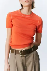 Top de punto color marrón con cuello redondo y manga corta. Detalle de ribete blanco en cuello y mangas.