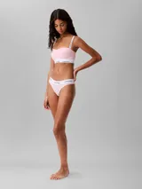 Conjunto de ropa interior Calvin Klein, compuesto por un corpiño bandeau y una bombacha colaless, ambos en color rosa claro con banda elástica blanca con el logo de la marca.