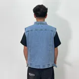Chaleco de denim celeste con cuello camisero, cierre frontal con botones metálicos, dos bolsillos frontales con solapa y logo bordado en el pecho.