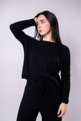 Buzo de punto color negro, con cuello redondo y lazo ajustable en la cintura.
