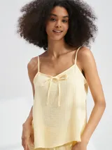 Musculosa color amarillo pálido con tirantes finos y detalle de lazo en el escote.