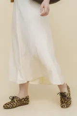 Mocasín tipo boat shoe con estampado de vaca en tonos marrón y blanco, confeccionado en cuero. Cuenta con cordones de cuero marrón oscuro y suela de goma.