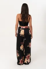 Pantalón palazzo negro con estampado floral en tonos rosa, naranja y amarillo. Tiene cintura alta con elástico.