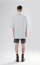 Camisa de manga corta color verde agua, con cuello clásico y calce oversize. Presenta un canesú en la espalda.