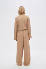 Pantalón de calce ancho y tiro alto, color beige con textura.